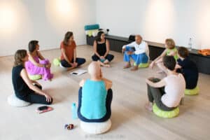 Groupe de personnes assises en cercle lors d'un atelier de bien-être chez Re-source, écoutant attentivement un intervenant